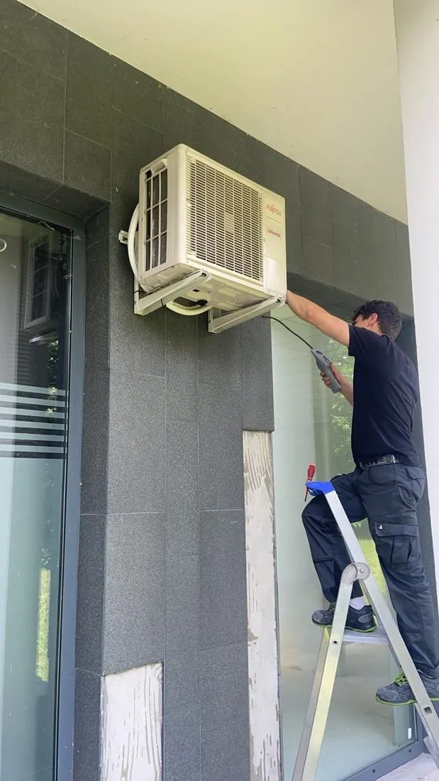 Technicien Clim69 sur échelle pour une intervention en hauteur